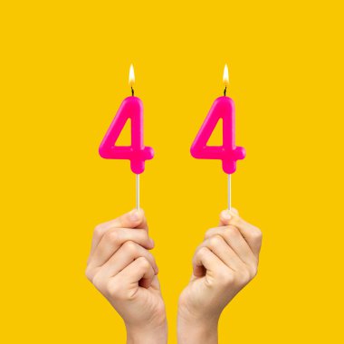 44 numaralı doğum günü mumlarını tutan eller - Sarı arkaplan