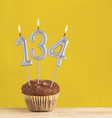 134 numaralı mumlu çikolatalı kek. Sarı arka planda doğum günü pastası.