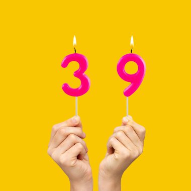 39 numaralı doğum günü - Eller fuşya renkli mumları tutuyor