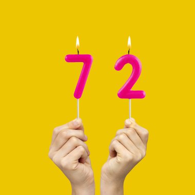 Ellerinde 72 numaralı doğum günü mumları var.