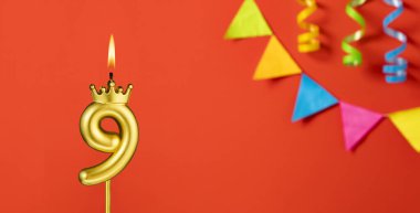 Turuncu arka planda 9 numaralı doğum günü mumu.