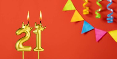 Turuncu arka planda 21 numaralı doğum günü mumu.