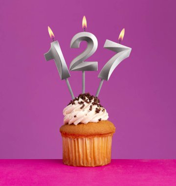 127 numaralı doğum günü mumu ve menekşeli kek.