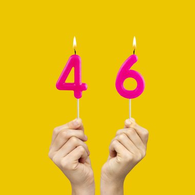 46 numaralı doğum günü mumlarını tutan eller - Sarı arkaplan