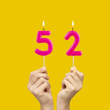 52 numaralı doğum günü mumlarını tutan eller - Sarı arkaplan