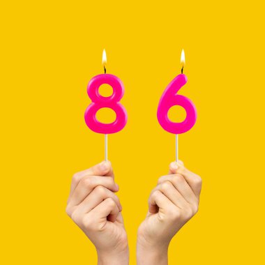86 numaralı doğum günü mumlarını tutan eller - Sarı arkaplan