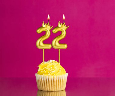 Sarı doğumgünü keki 22 numaralı mum ile pembe arka planda doğum günü kartı