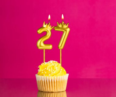 27 numaralı mumla doğum günü kutlaması - Pembe arka planda sarı kek