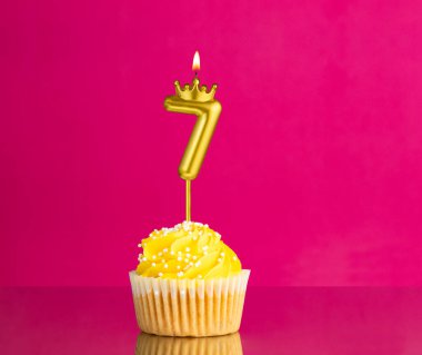 7 numaralı mumla doğum günü kutlaması - Pembe arka planda sarı kek