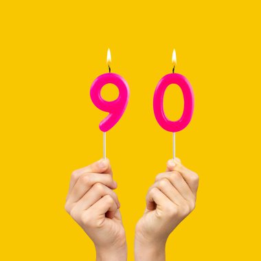 90 numaralı doğum günü mumlarını tutan eller - Sarı arkaplan