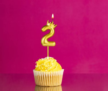 Sarı doğumgünü pastası, üzerinde 2 numaralı mum olan pembe arka planda doğum günü kartı.