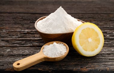 Kase ve kaşıkta kabartma tozu ile sarı limon meyvesi.