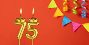 Turuncu arka planda 75 numaralı doğum günü mumu.