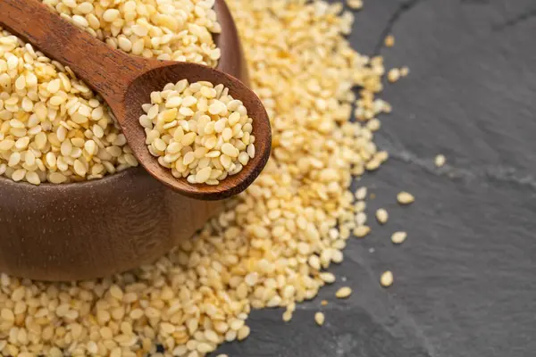 Bir kaşık ve kâsede çiğ ve kurutulmuş susam tohumları - Sesamum indicum