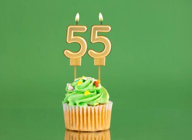 55 numaralı doğum günü mumu. Yeşil arka planda kek.