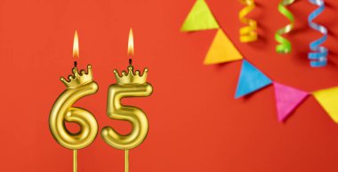 Turuncu arka planda 65 numaralı doğum günü mumu.