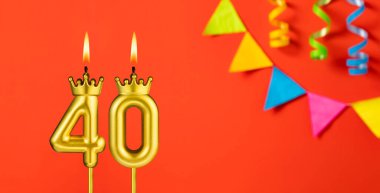 40 numaralı mum - Turuncu arka planda doğum günü kutlaması flamalarıyla