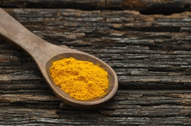 Kaşıktaki organik zerdeçal tozu Curcuma longa
