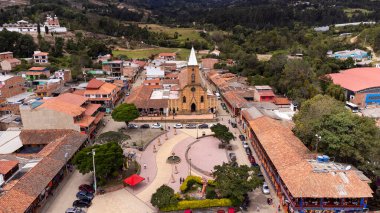 Raquira, Boyaca, Kolombiya. 11 Mayıs 2025. Kasabanın ana kilisesinin panoramik drone görüntüsü.