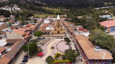 Raquira, Boyaca, Kolombiya. 11 Mayıs 2025. Kasabanın ana kilisesinin panoramik drone görüntüsü.