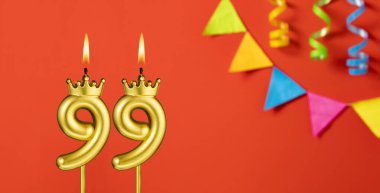 99 numaralı doğum günü mumu turuncu arka planda flama ile