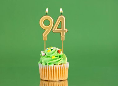 Yeşil zemin üzerinde mum ve kek olan doğum günü kartı 94 numara.