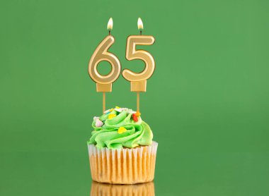 65 numaralı doğum günü mumu. Yeşil arka planda kek.