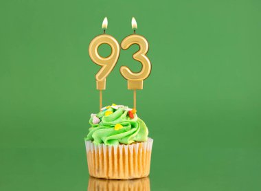 93 numaralı doğum günü mumu. Yeşil arka planda kek.