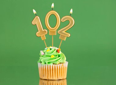 Yeşil arka planda 102 numaralı muma sahip doğum günü kartı.