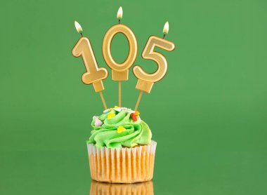 105 numaralı doğum günü mumu. Yeşil arka planda kek.
