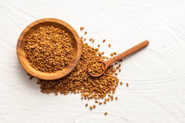 Trigonella foenum graecum adlı kâse ve kaşıkta kurutulmuş organik çemen otu tohumları.