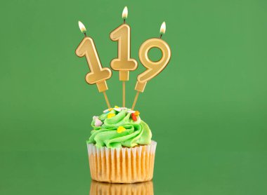 119 numaralı doğum günü mumu. Yeşil arka planda kek.