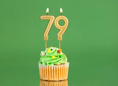 79 numaralı doğum günü mumu. Yeşil arka planda kek.