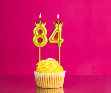 84 numaralı mumla doğum günü kutlaması - Pembe arka planda sarı kek
