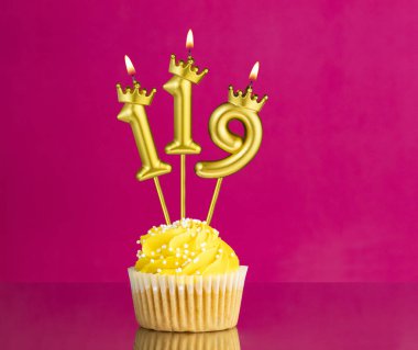 Sarı doğumgünü pastası, üzerinde 119 numara mum olan pembe arka planda doğum günü kartı.