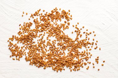 Beyaz arka plana yayılmış organik çınar otu tohumları