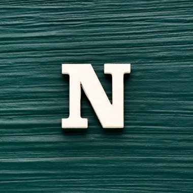 Alfabe harfi N, koyu yeşil kırsal arka planda beyaz parça.