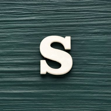 Alfabe harfi S, koyu yeşil kırsal arkaplan üzerine beyaz parça.