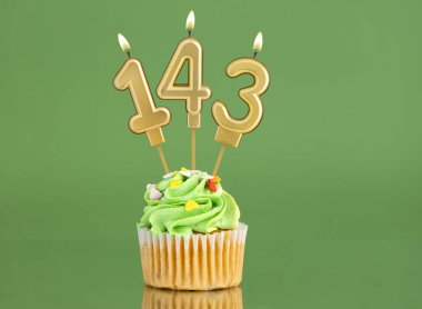 143 numaralı doğum günü mumu. Yeşil arka planda kek.