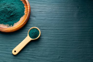 Bir kaşık ve kâsede organik spirulina tozu.