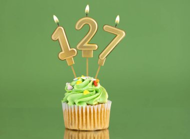 127 numaralı doğum günü mumu. Yeşil arka planda kek.