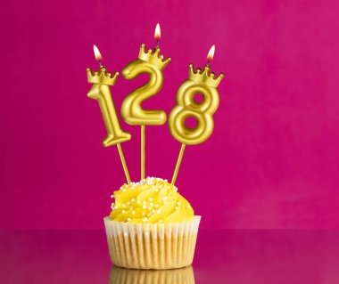 128 numaralı mumla doğum günü kutlaması - Pembe arka planda sarı kek