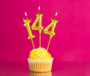 144 numaralı mumla doğum günü kutlaması - Pembe arka planda sarı kek