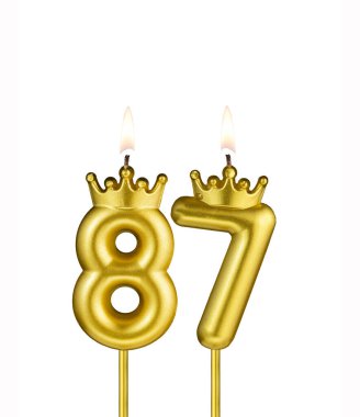Beyaz arkaplanda 87 numaralı doğum günü mumu.