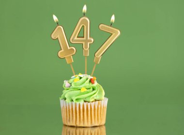 147 numaralı doğum günü mumu. Yeşil arka planda kek.