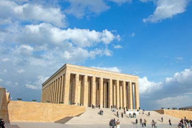 Ankara, Türkiye 'deki Anitkabir' in görkemli manzarası, Atatürk 'ün mozolesi. Geniş anıt, etkileyici mimarisi ve çevresini gösteren canlı mavi gökyüzüne karşı gururla duruyor. İnsanlar siteyi ziyaret ederken görülebilir, bir s eklenebilir