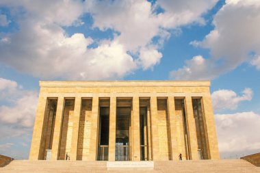 Ankara, Türkiye 'deki Anitkabir, Atatürk' ün mozolesinin düşük açılı görüntüsü. Büyük, açık renkli taş yapı geniş bir merdiven, sayısız sütun ve geniş bir girişe sahiptir. Parçalı bulutlu bir gökyüzü bir arkaplan sağlar.