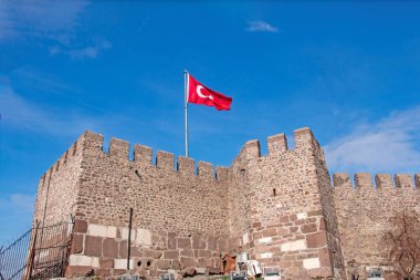 Beyaz hilal şeklinde bir Türk bayrağı ve açık mavi gökyüzüne konmuş bir bayrak direğinin üzerinde yavaşça dalgalanan yıldız. Bayrak gururla karşımızda duruyor. Kadim bir taş kale duvarına, pürüzlü dokusuna ve crenellasyonlarına bakıyor..