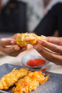 Ahşap masa üzerinde kırmızı biber, domates ve sosla servis edilen kızarmış karides gamzesi (udang rambutan).