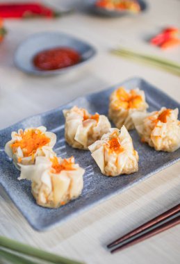 Ahşap masa üzerinde acı biber, domates ve sos ile servis edilen buğulanmış tavuklu gamsum.